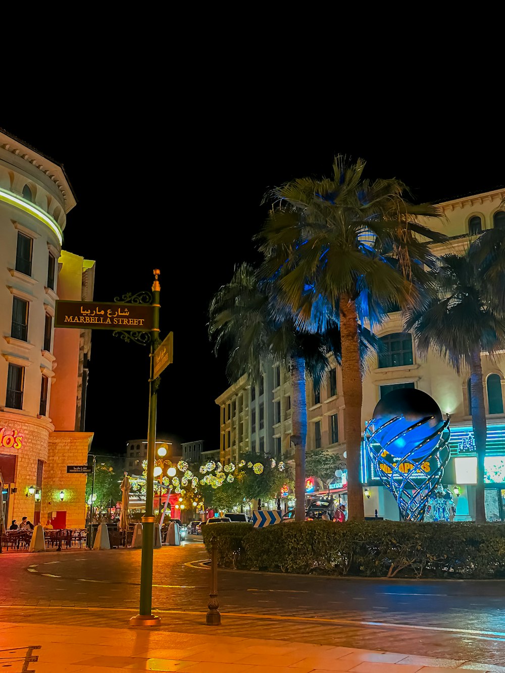 a city street at night with palm trees