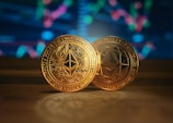 two gold coin sitting on top of a wooden table