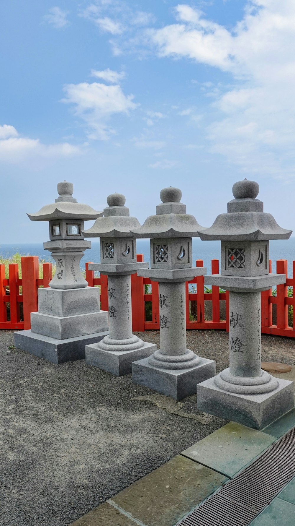 a row of stone lanterns in front of a red fence