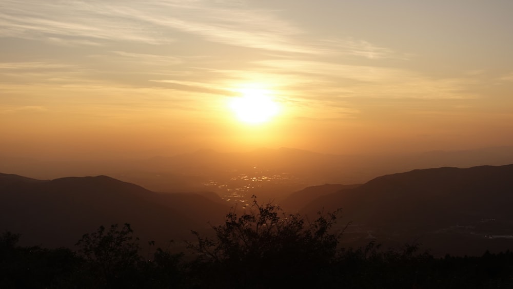 the sun is setting over a mountain range