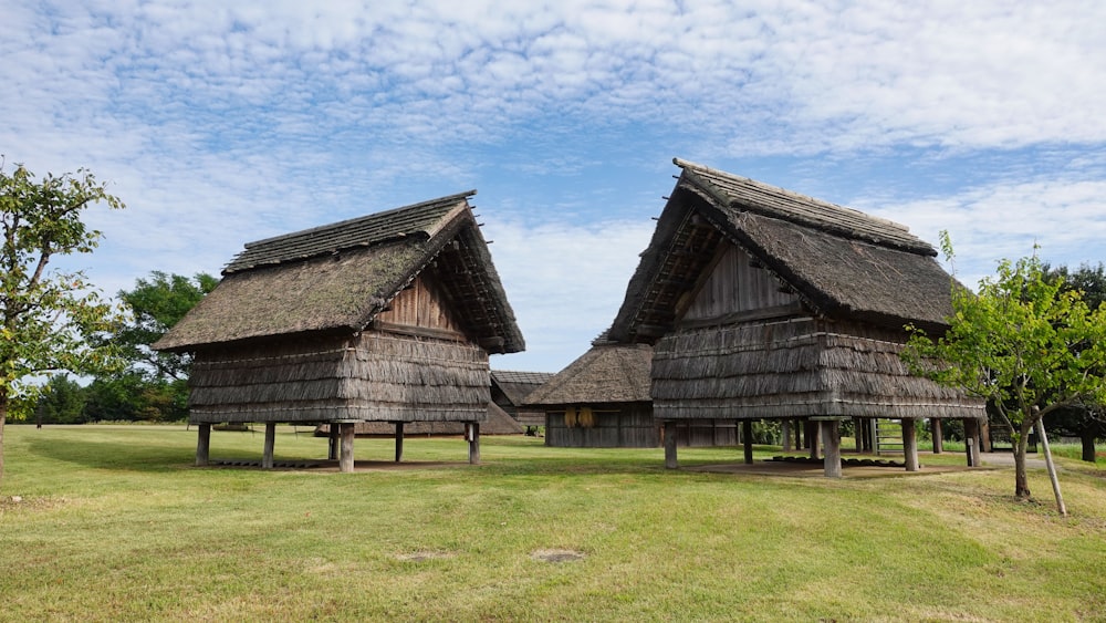 a couple of wooden buildings sitting on top of a lush green field