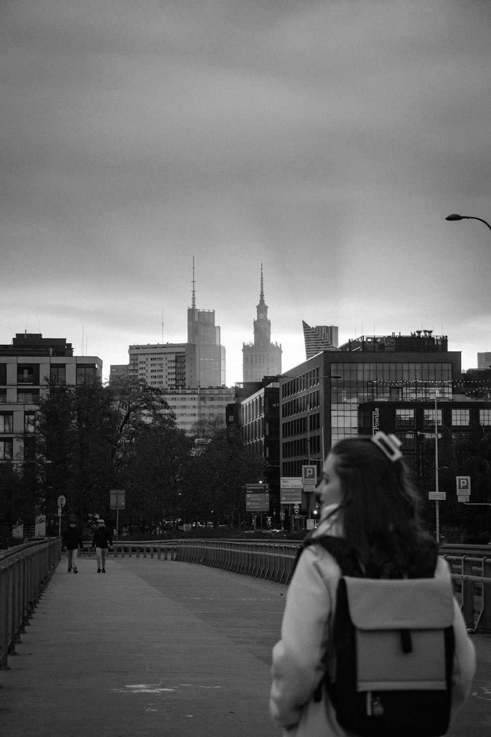 a woman walking across a bridge in a city