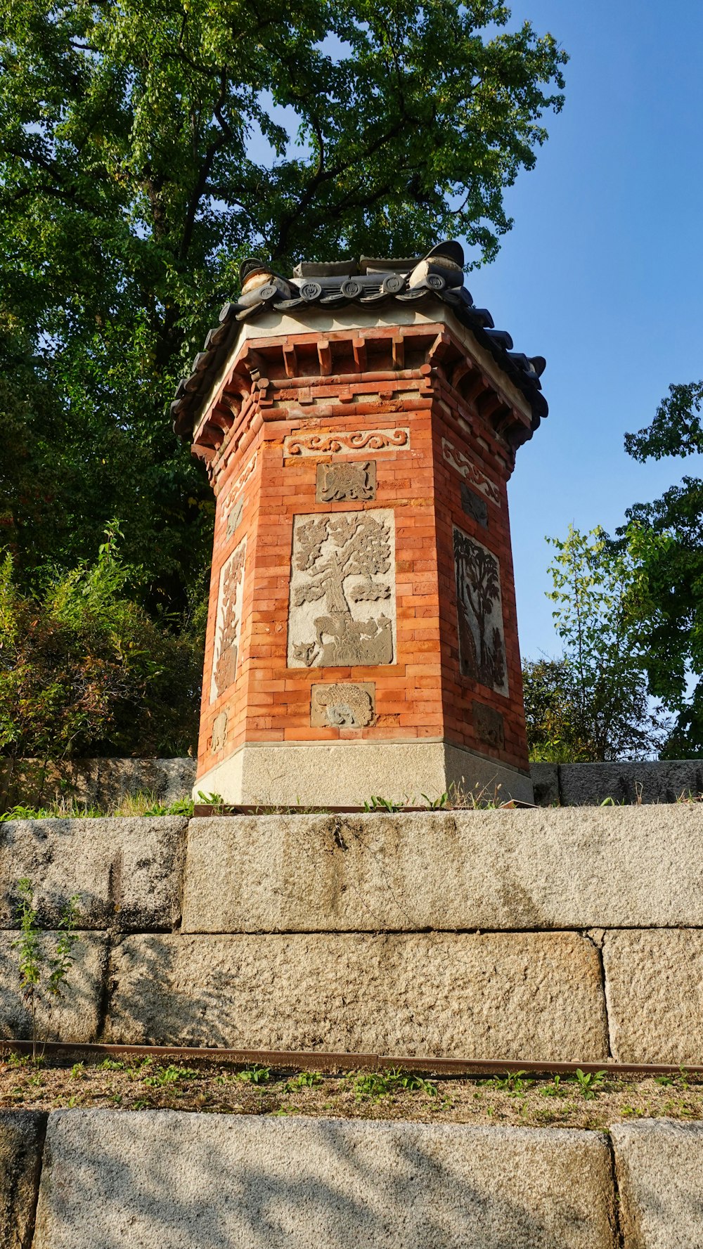 una pequeña torre de ladrillo asentada en lo alto de un muro de piedra