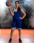 Individual portrait of a high school basketball player holding a ball, shot against a sleek navy backdrop.