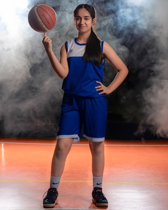 Individual portrait of a high school basketball player holding a ball, shot against a sleek navy backdrop.