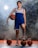 A person is standing with a confident pose, dressed in a blue and white sports uniform. They are holding a basketball under their right arm while their left foot is resting on another basketball. There are three additional basketballs placed around on the ground. The background is smoky, giving a dramatic effect, with light shining through the smoke.