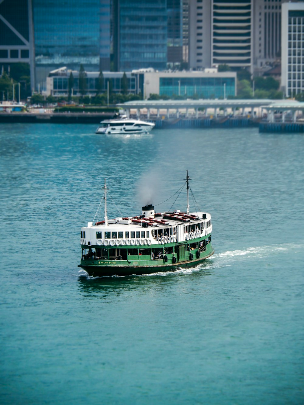 a green and white boat traveling on a body of water