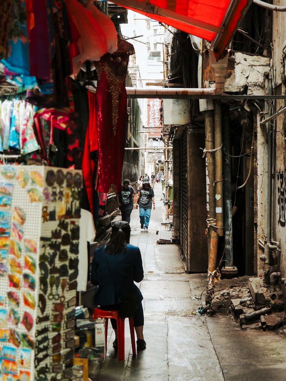 a woman sitting on a chair in a narrow alleyway