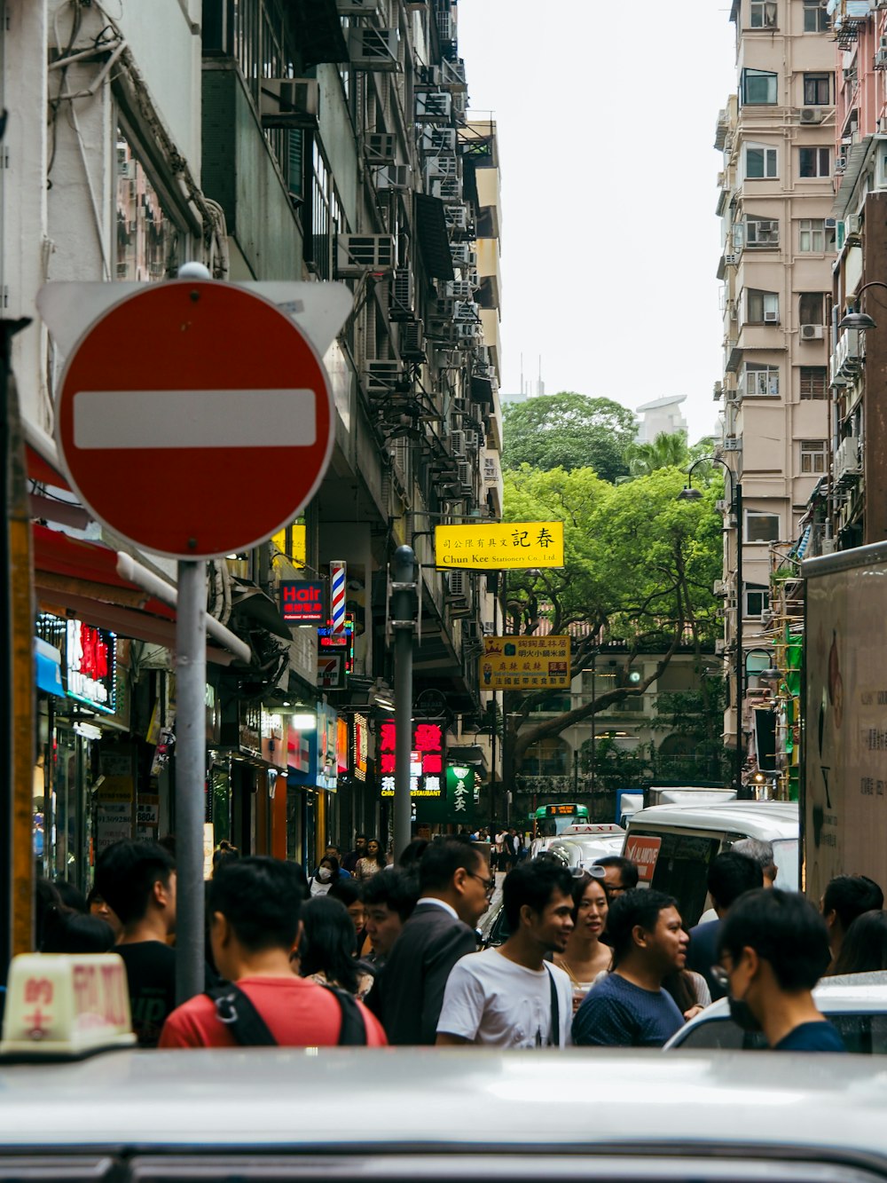 a group of people walking down a street next to tall buildings