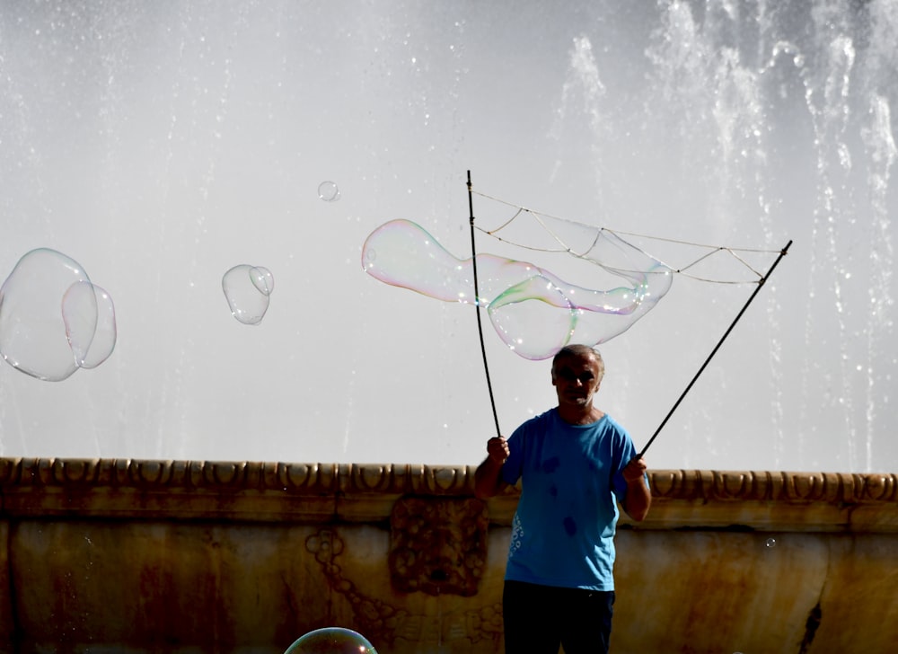 a man is holding a kite in front of a fountain
