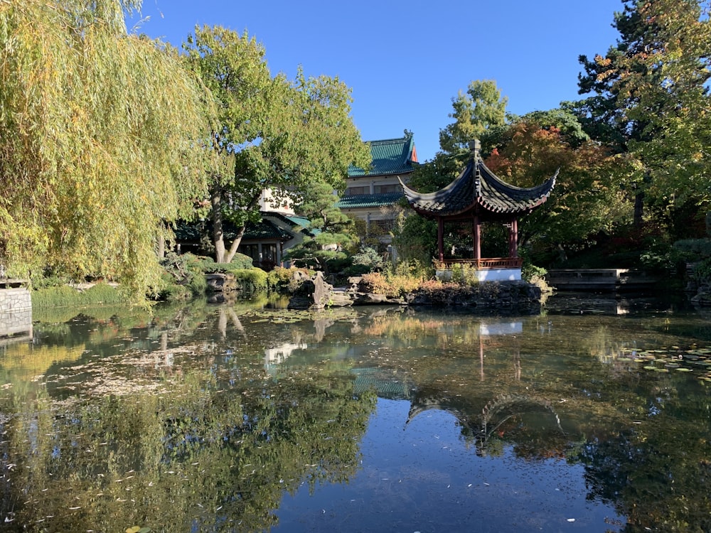 a pond in a park with a pavilion in the background