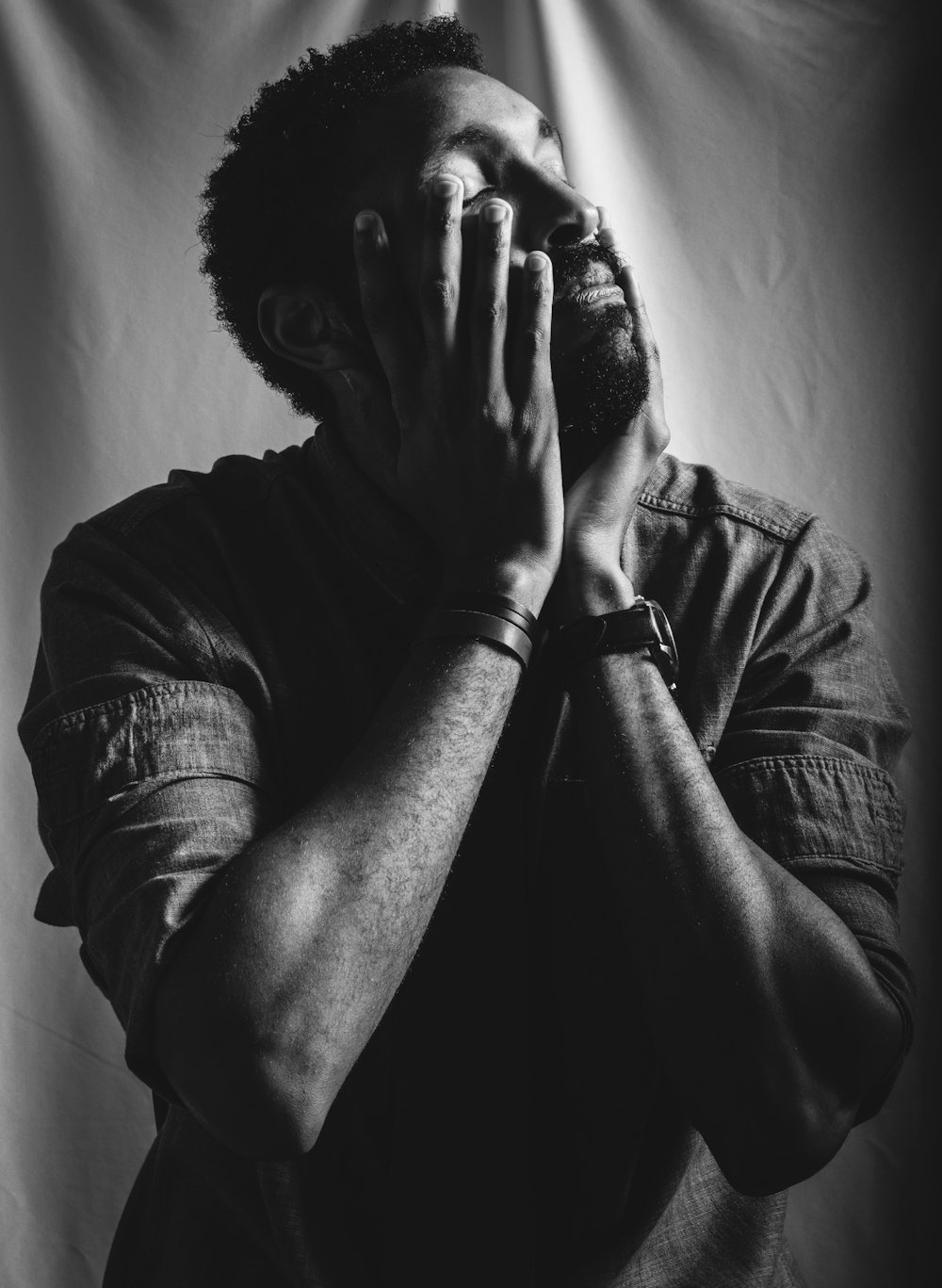 a black and white photo of a man covering his face