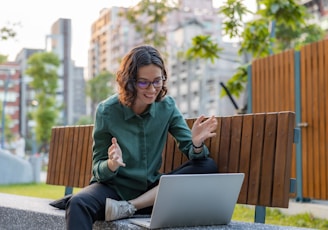 a woman sitting on a bench using a laptop