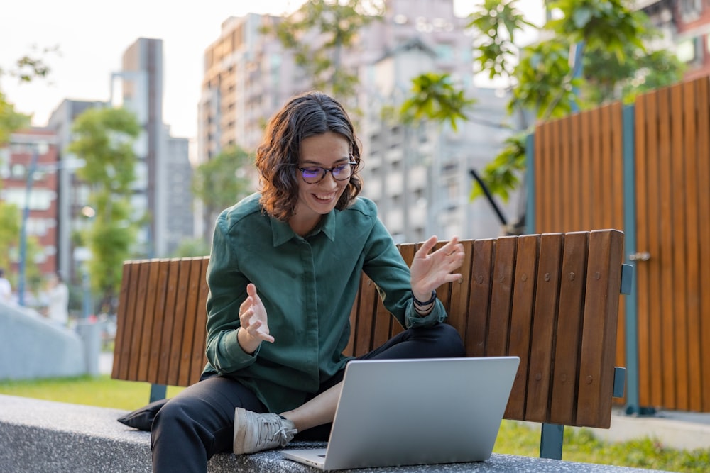 a woman sitting on a bench using a laptop