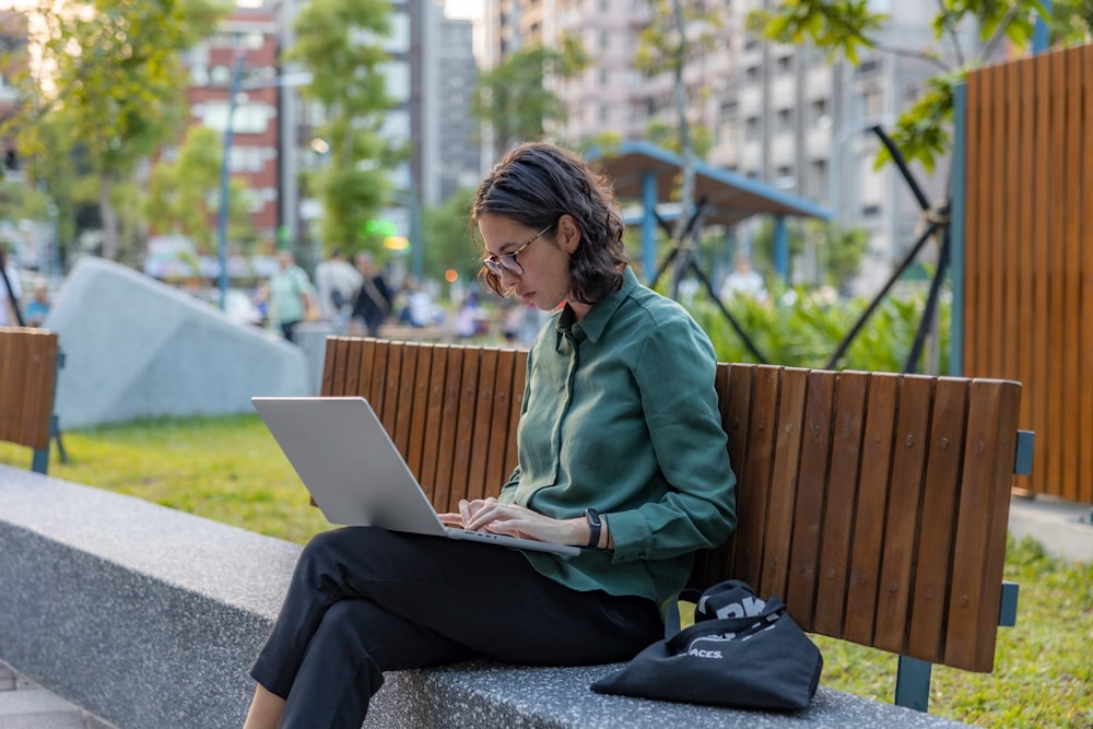 a woman sitting on a bench using a laptop