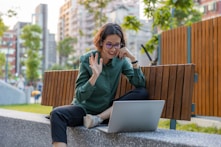a woman sitting on a bench with a laptop