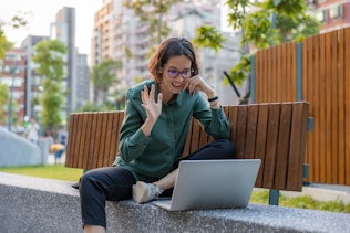 a woman sitting on a bench with a laptop