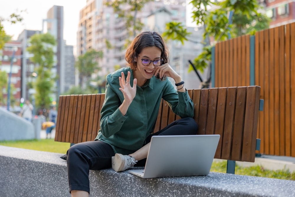 a woman sitting on a bench with a laptop