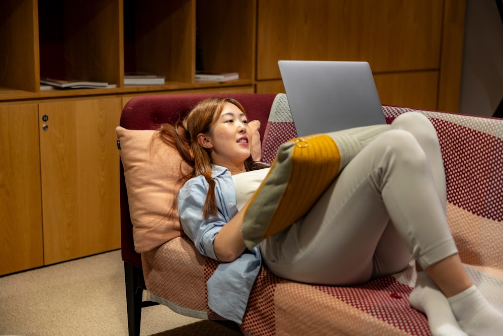 a woman laying on a couch using a laptop computer