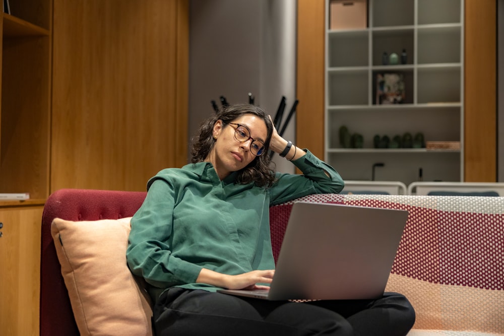 una mujer sentada en un sofá usando una computadora portátil