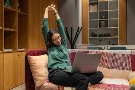 A relaxed physiotherapist checking mission offers on a laptop in a cozy home setting.
