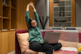 A relaxed physiotherapist checking mission offers on a laptop in a cozy home setting.