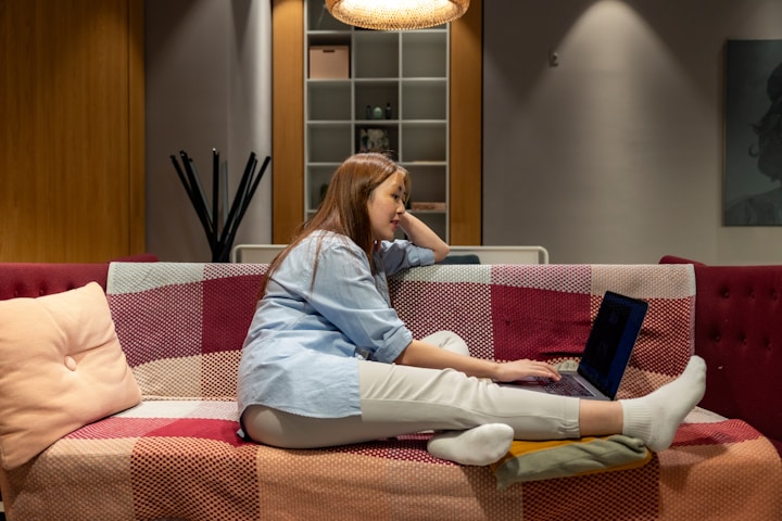 a woman sitting on a couch using a laptop computer