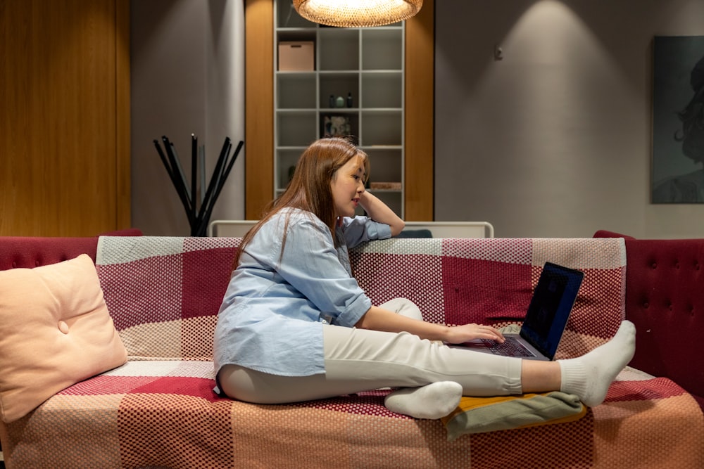 a woman sitting on a couch using a laptop computer