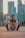 a man sitting on the ground in front of a city skyline