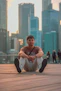 a man sitting on the ground in front of a city skyline