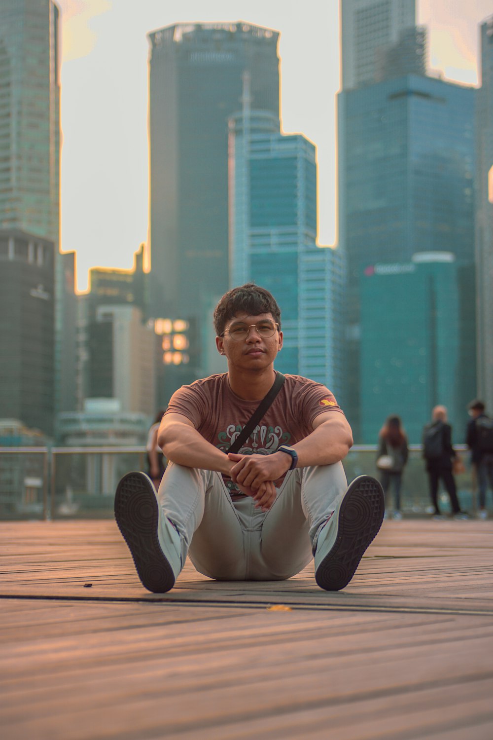 a man sitting on the ground in front of a city skyline