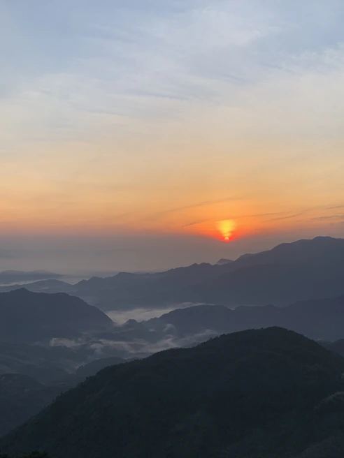 A serene landscape shot of a sunrise over a misty mountain range