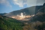 A serene view of distant mountains with steam rising from geothermal vents.
