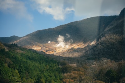 A serene view of distant mountains with steam rising from geothermal vents.