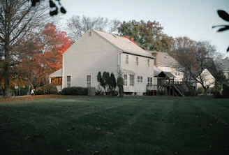 New siding being carefully installed on a cozy suburban house with autumn leaves around.