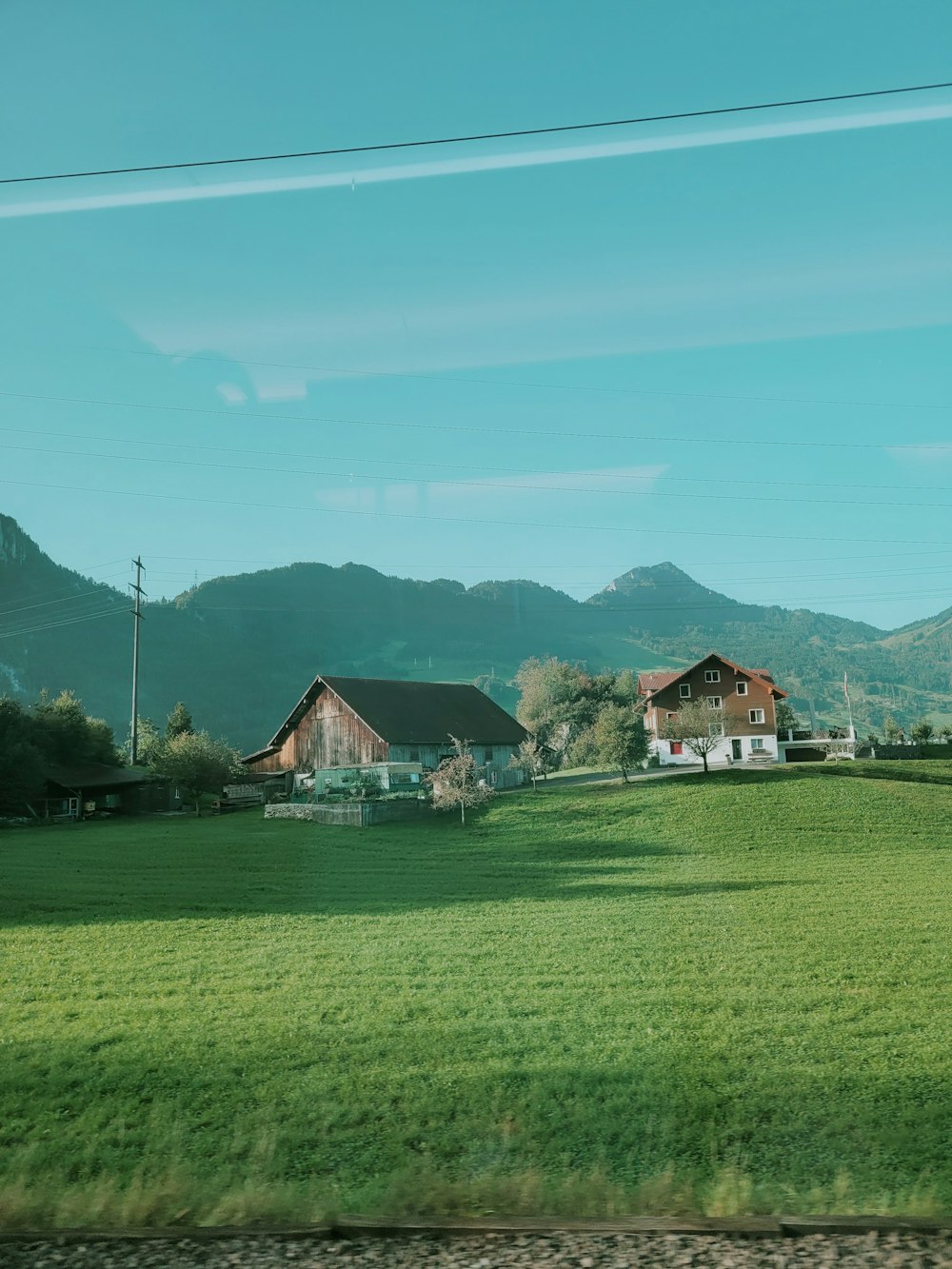 a green field with houses and mountains in the background