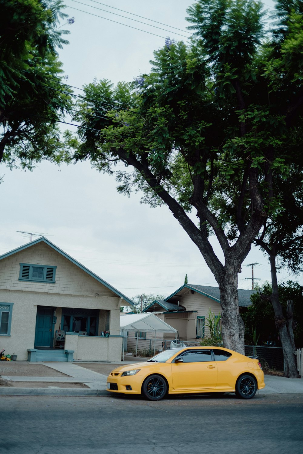a yellow car parked in front of a tree