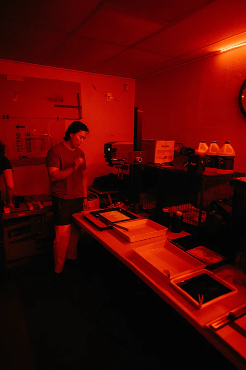 A student working under the red light of the darkroom