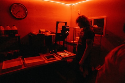 Photo of a technician carefully developing photographic prints in a darkroom.