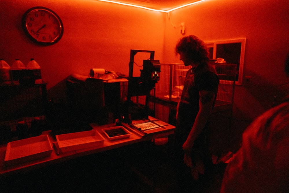 a woman standing in a dark room with a clock on the wall