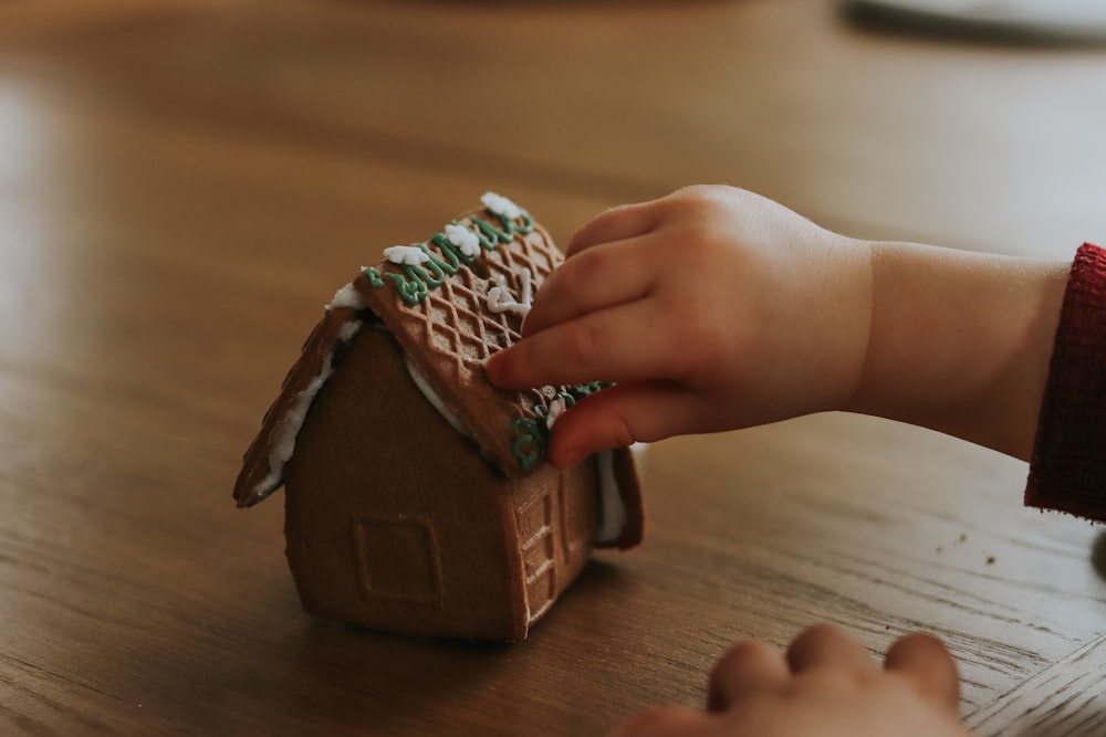 Un niño está decorando una casa de pan de jengibre