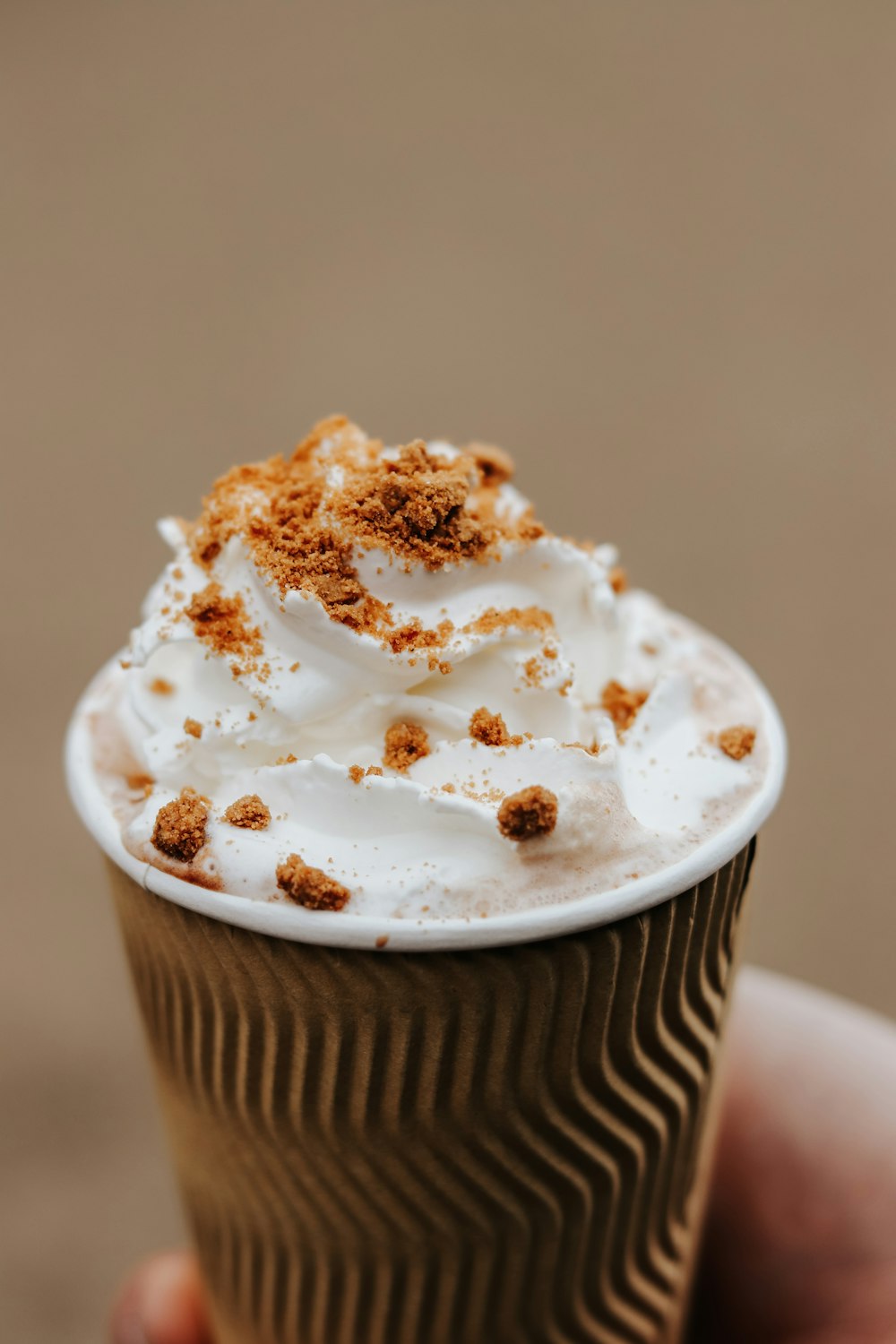 a hand holding a cup of whipped cream