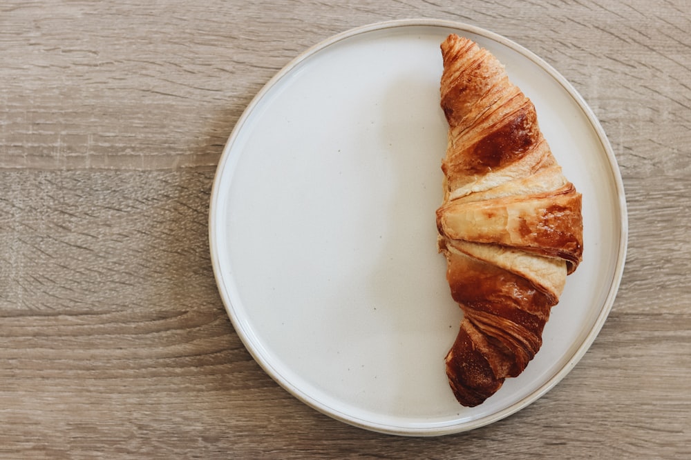 a croissant on a plate on a wooden table