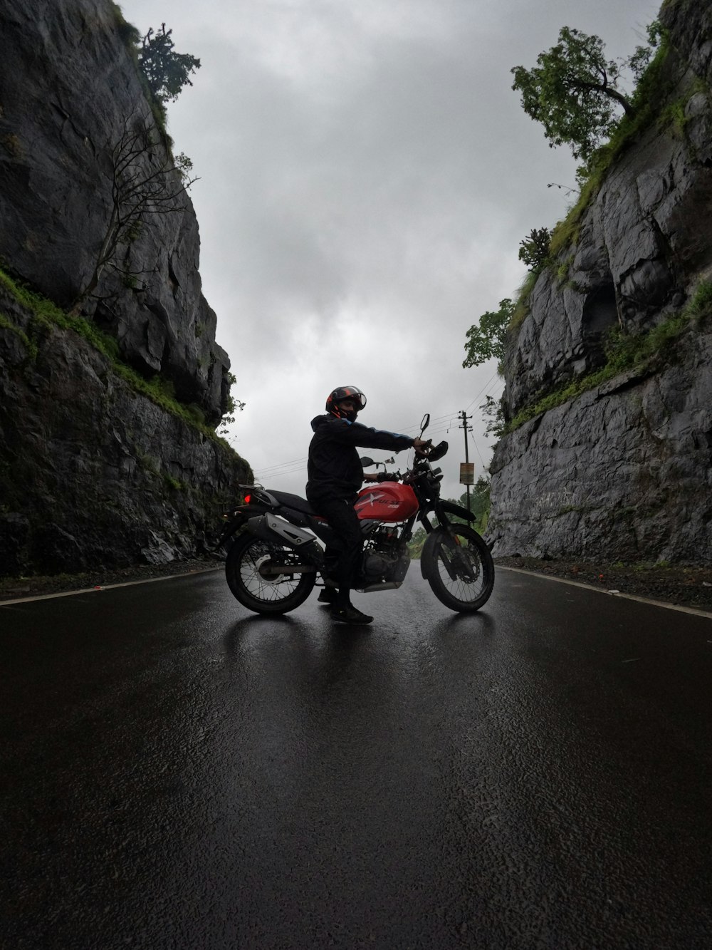 a man riding a motorcycle down a wet road