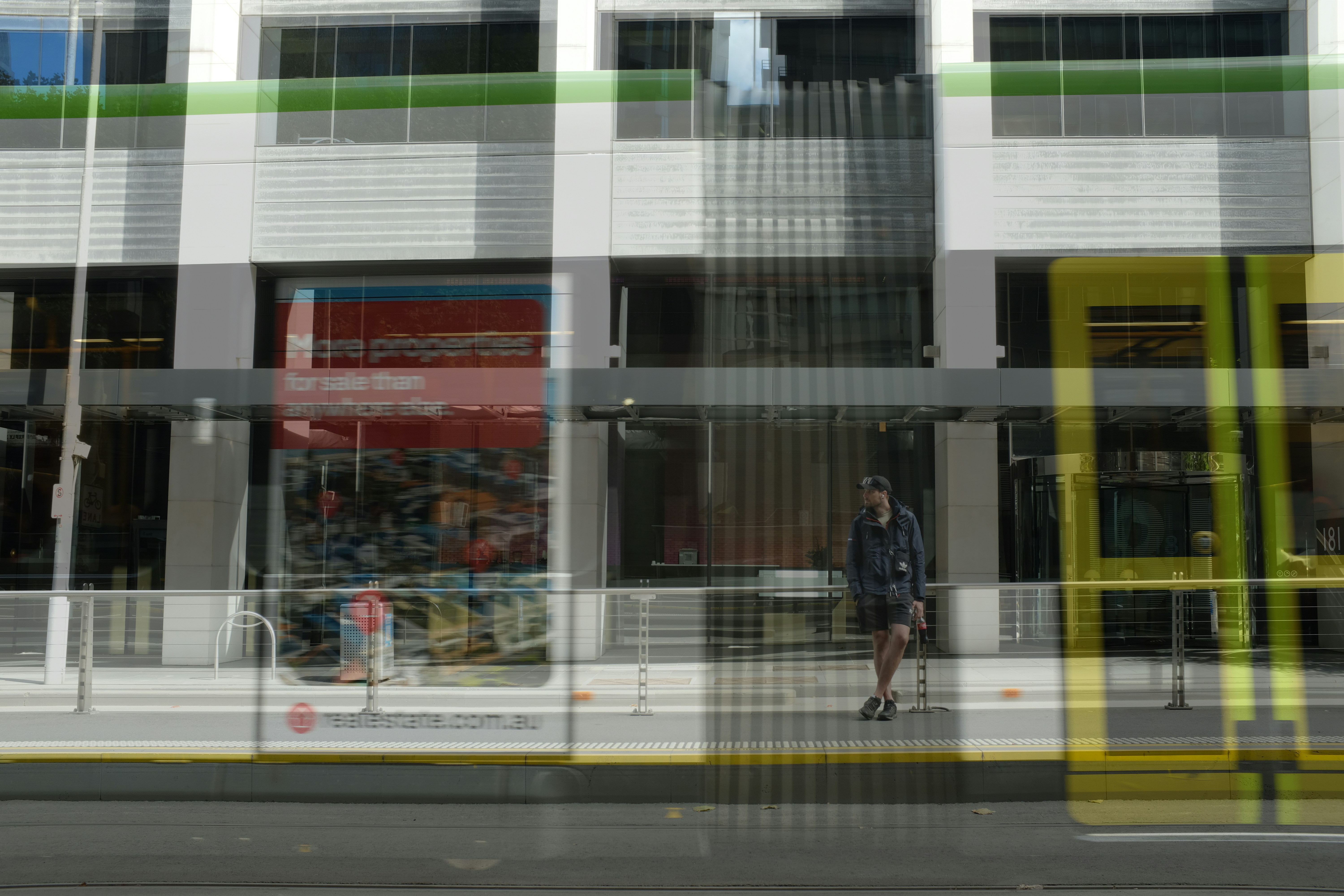 a man walking down a street past a tall building, 