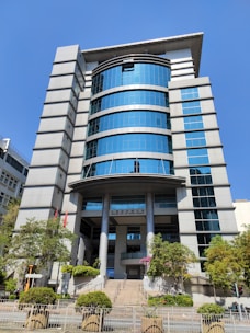 A modern office building with large windows and a landscaped area in front.