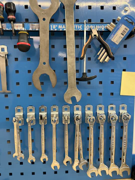 A display of various hand tools including hammers, screwdrivers, and wrenches hanging on a pegboard.