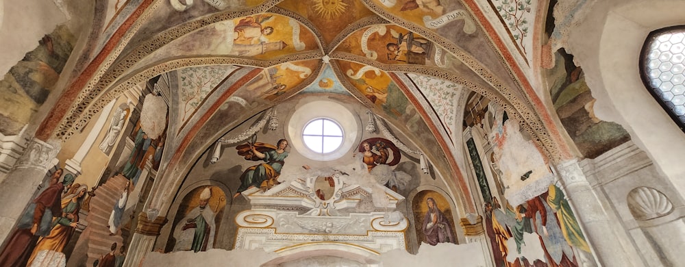 una iglesia con un techo abovedado muy alto y pinturas en las paredes