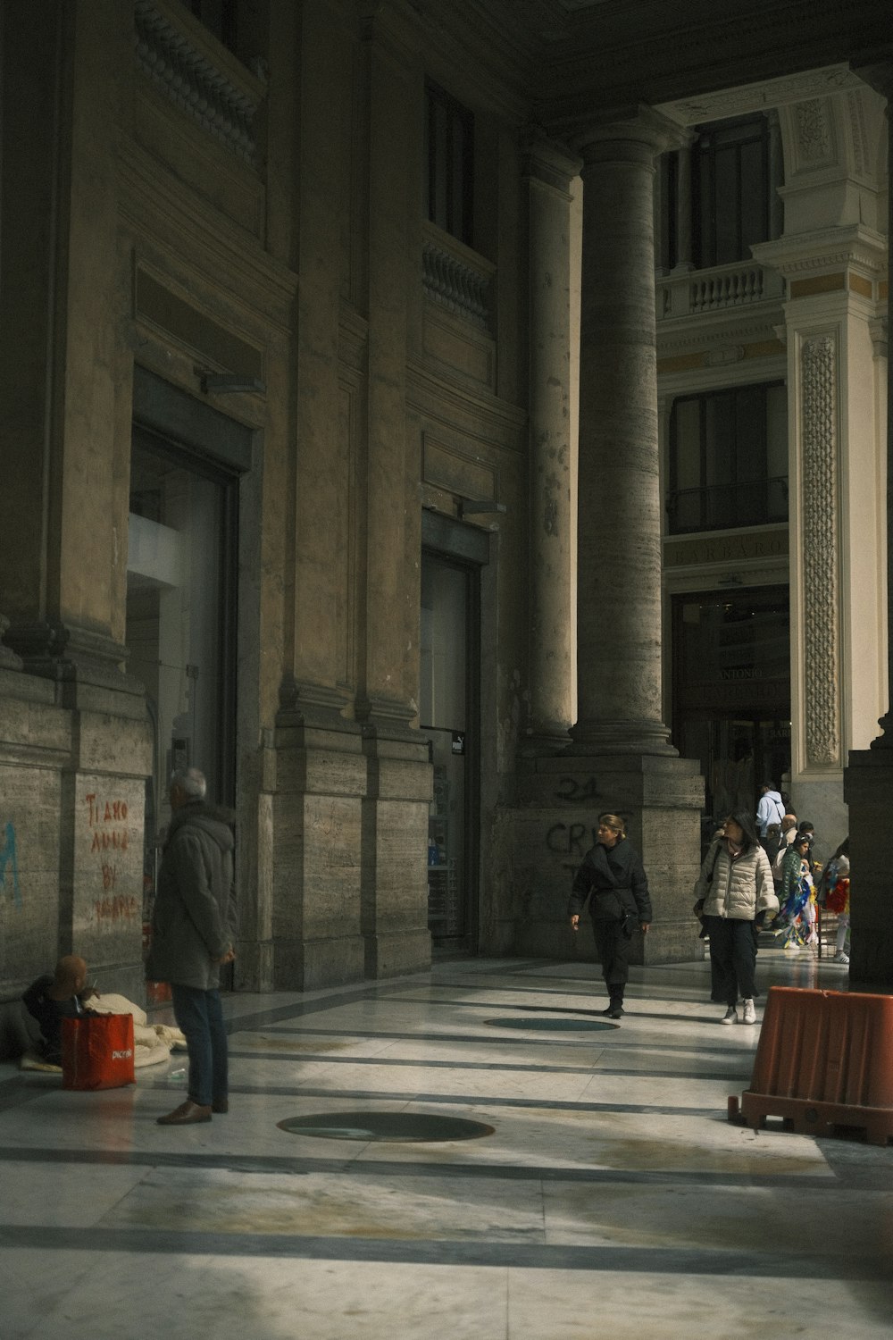 a group of people walking down a street next to tall buildings