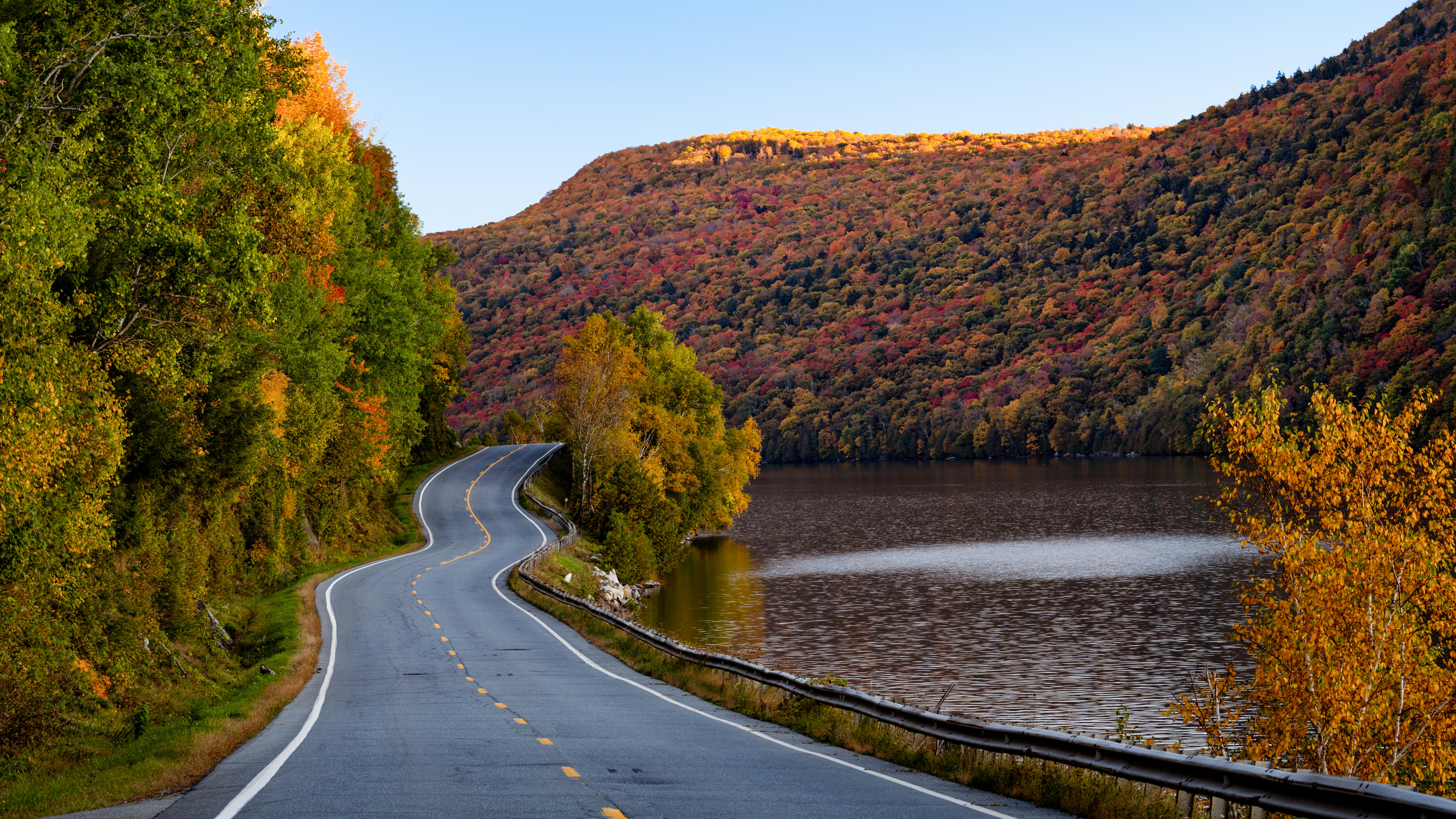 a winding road with a lake in the background, Fall lakeside